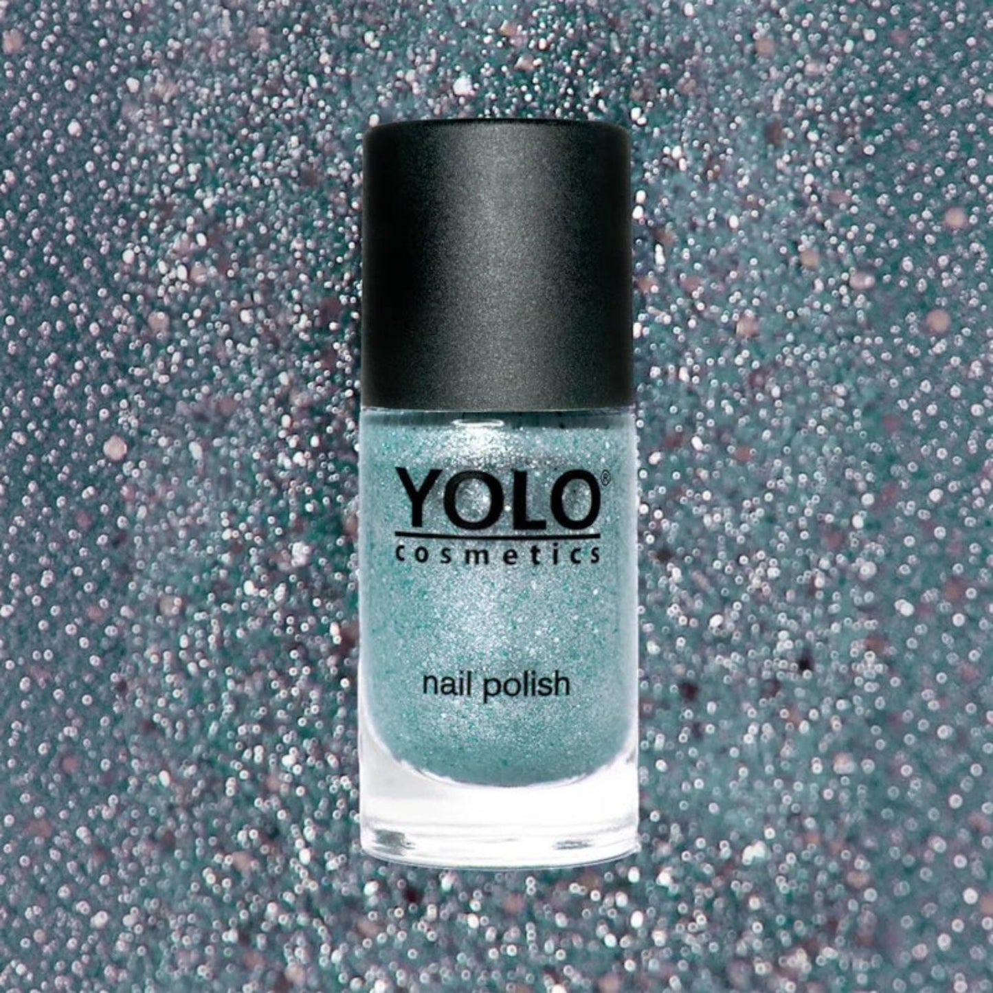 Said Salem YOLO Blue glitter nail polish in a glass bottle with a black cap against a sparkling teal background.