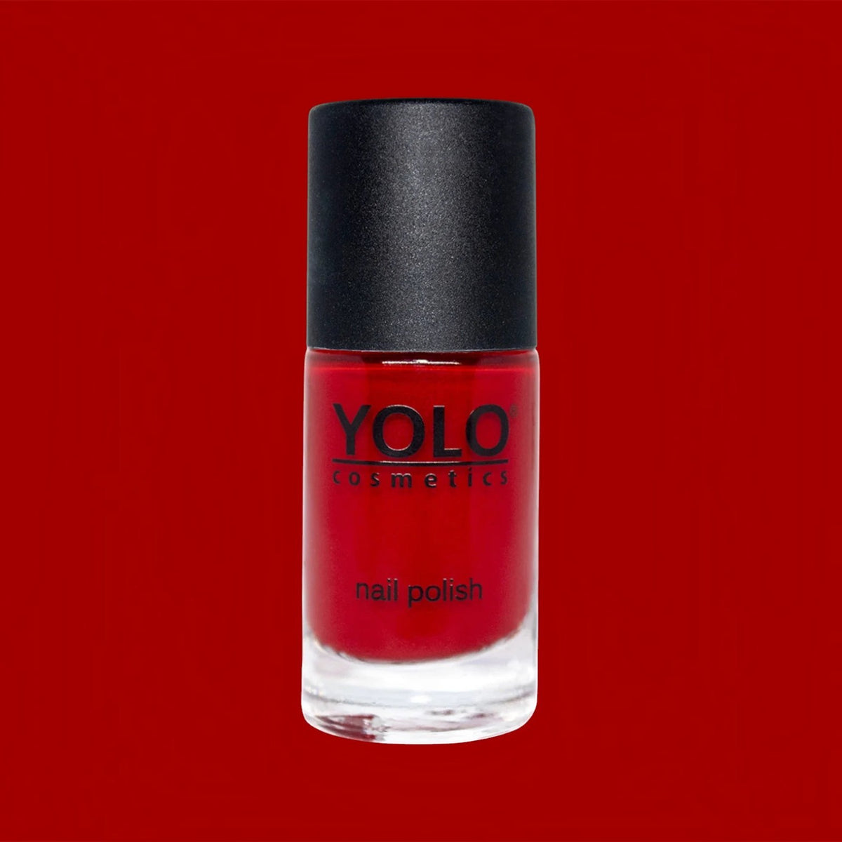 Said Salem YOLO Red nail polish in a clear glass bottle with a black cap against a vibrant red background.