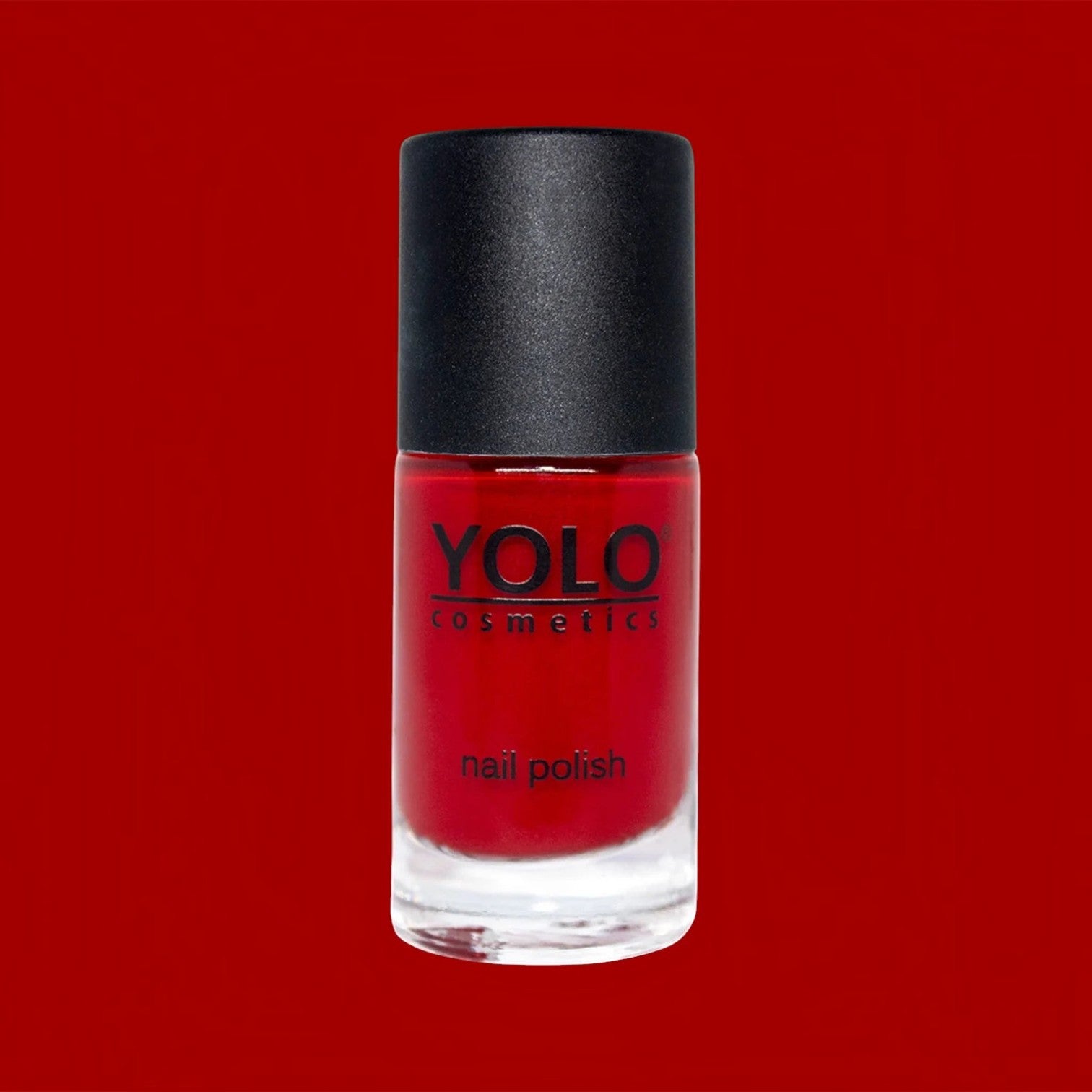 Said Salem YOLO Red nail polish in a clear glass bottle with a black cap against a vibrant red background.