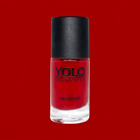 Said Salem YOLO Red nail polish in a clear glass bottle with a black cap against a vibrant red background.