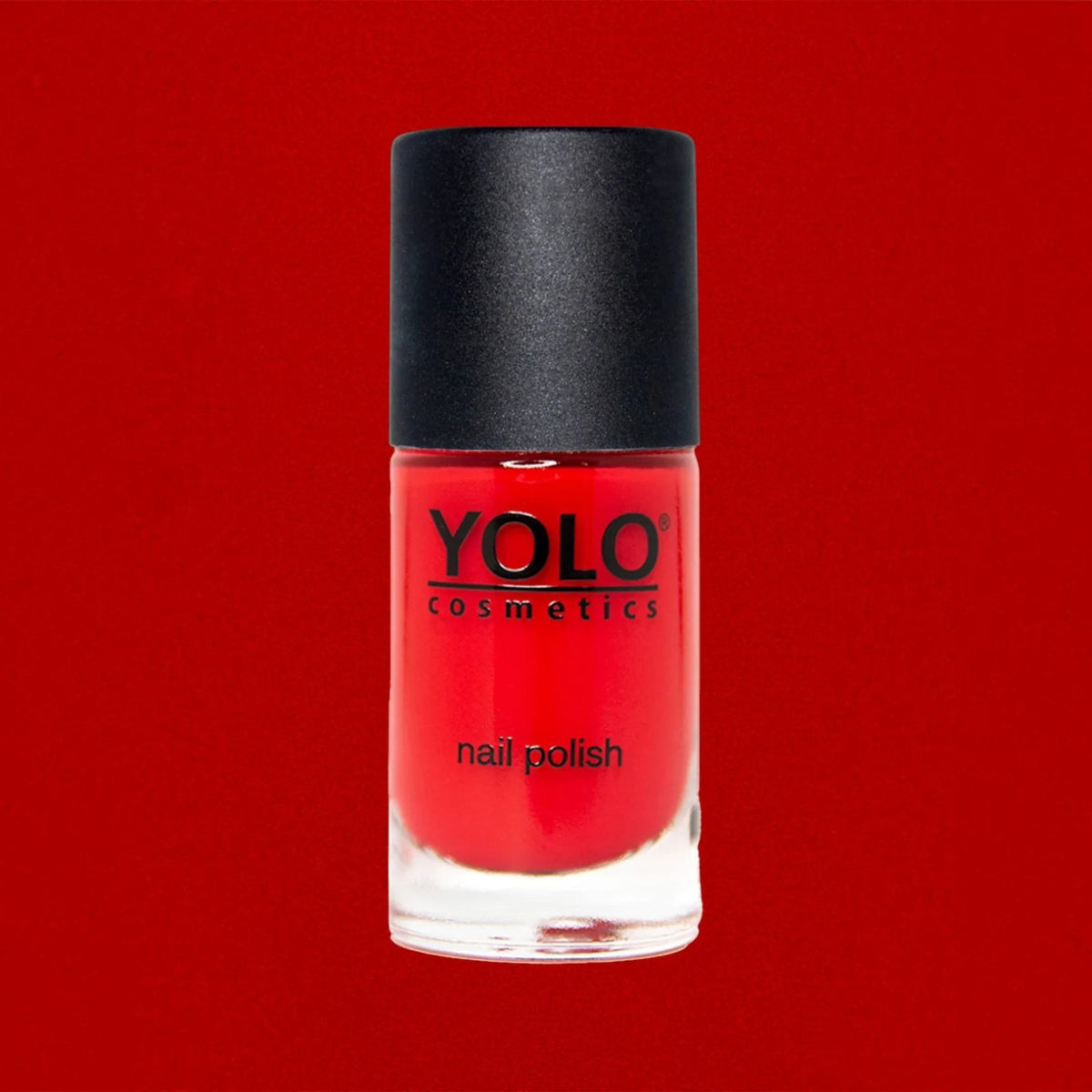 Said Salem YOLO Red nail polish in a clear glass bottle with a black cap against a vibrant red background.