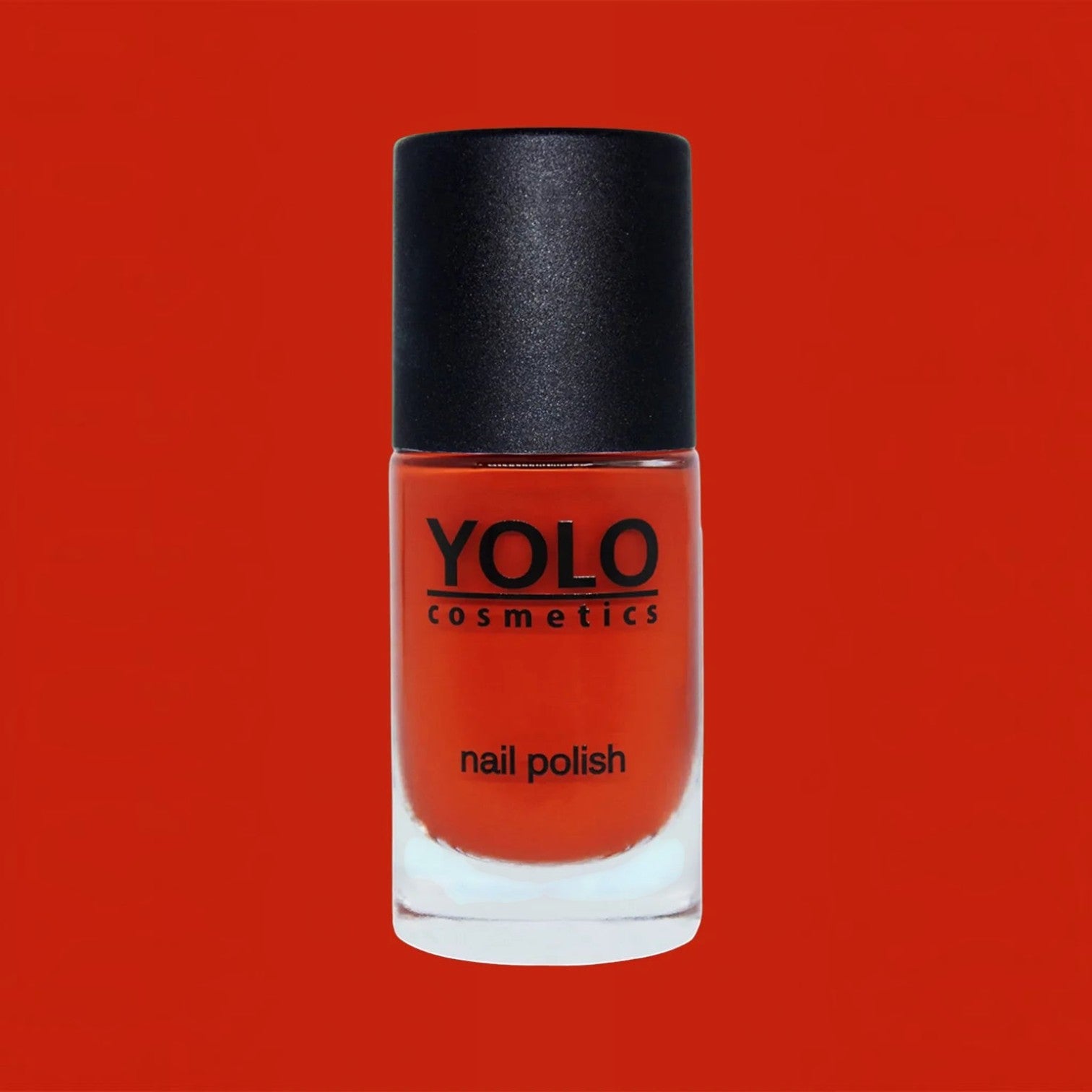 Said Salem YOLO Red nail polish in a clear glass bottle with a black cap against a vibrant red background